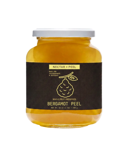 A glass jar of Nectar + Peel Bergamot Peel whole fruit preserves with a dark brown label and white lid, set against a plain white background.