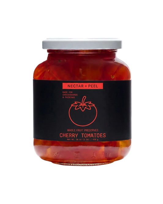 A glass jar of Nectar + Peel Cherry Tomatoes with a black label and white lid, set against a plain white background.