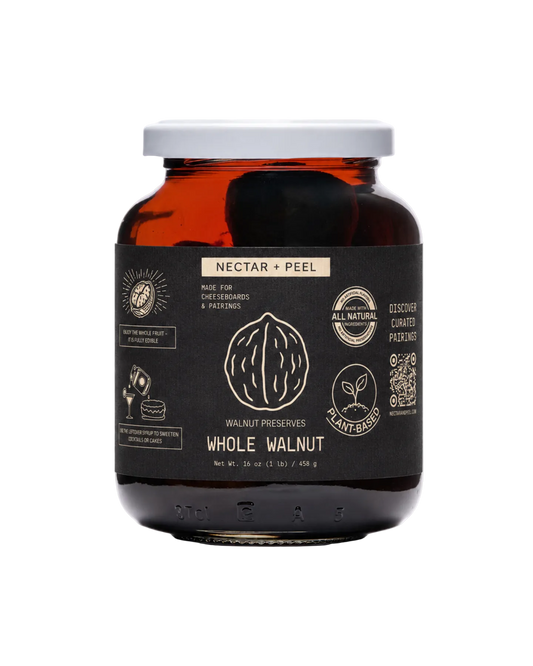 Jar of whole walnuts preserves in syrup with a black label on a white background